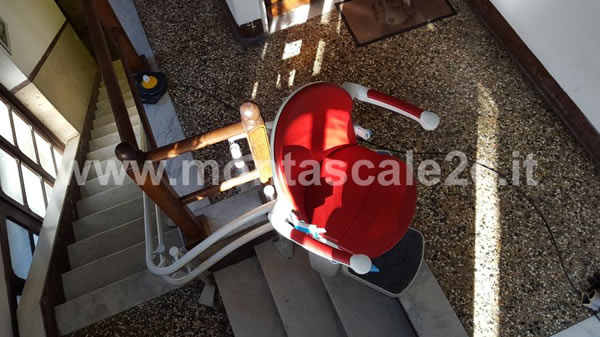 Poltroncina rossa di montascale curvilineo a doppia guida in edificio di Ceranesi