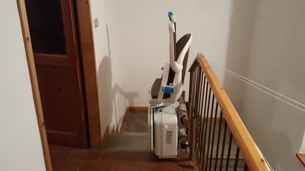 Montascale con poltroncina richiusa, modello curvilineo a doppia guida installato a Ponzone